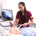Wintana Mokonnen works with a respiratory therapy manikin in a classroom setting.