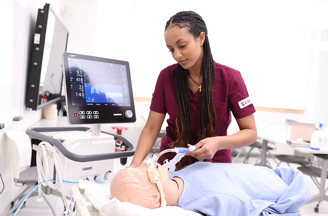 Wintana Mokonnen works with a respiratory therapy manikin in a classroom setting.