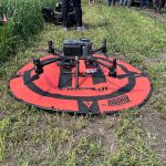 A drone rests on a red pad before being deployed