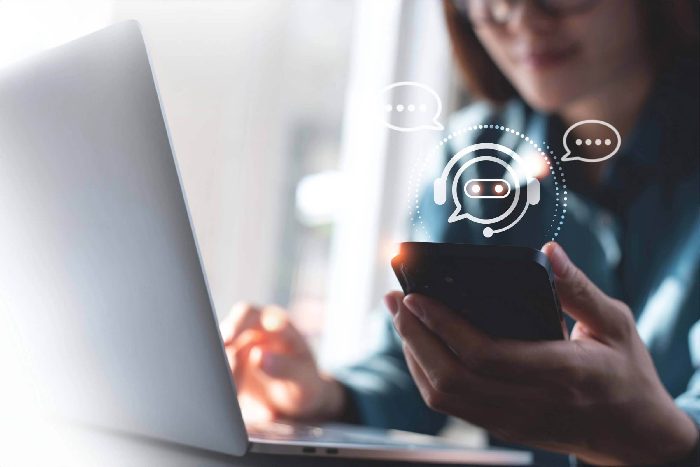 Woman working on a laptop computer and using a mobile phone.