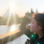 A person looking out over a body of water with a sunset behind a large tent in the background.