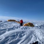 A researcher is walking along a series of tents set up in the Müller Ice Cap.