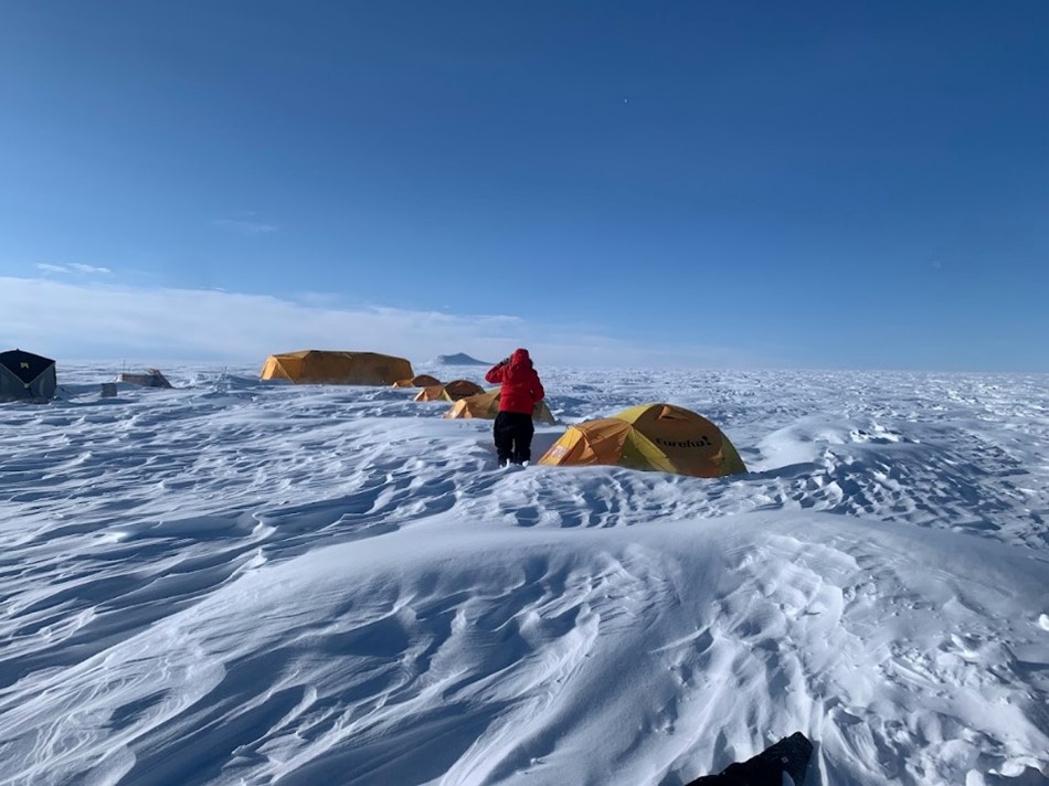 A researcher is walking along a series of tents set up in the Müller Ice Cap.