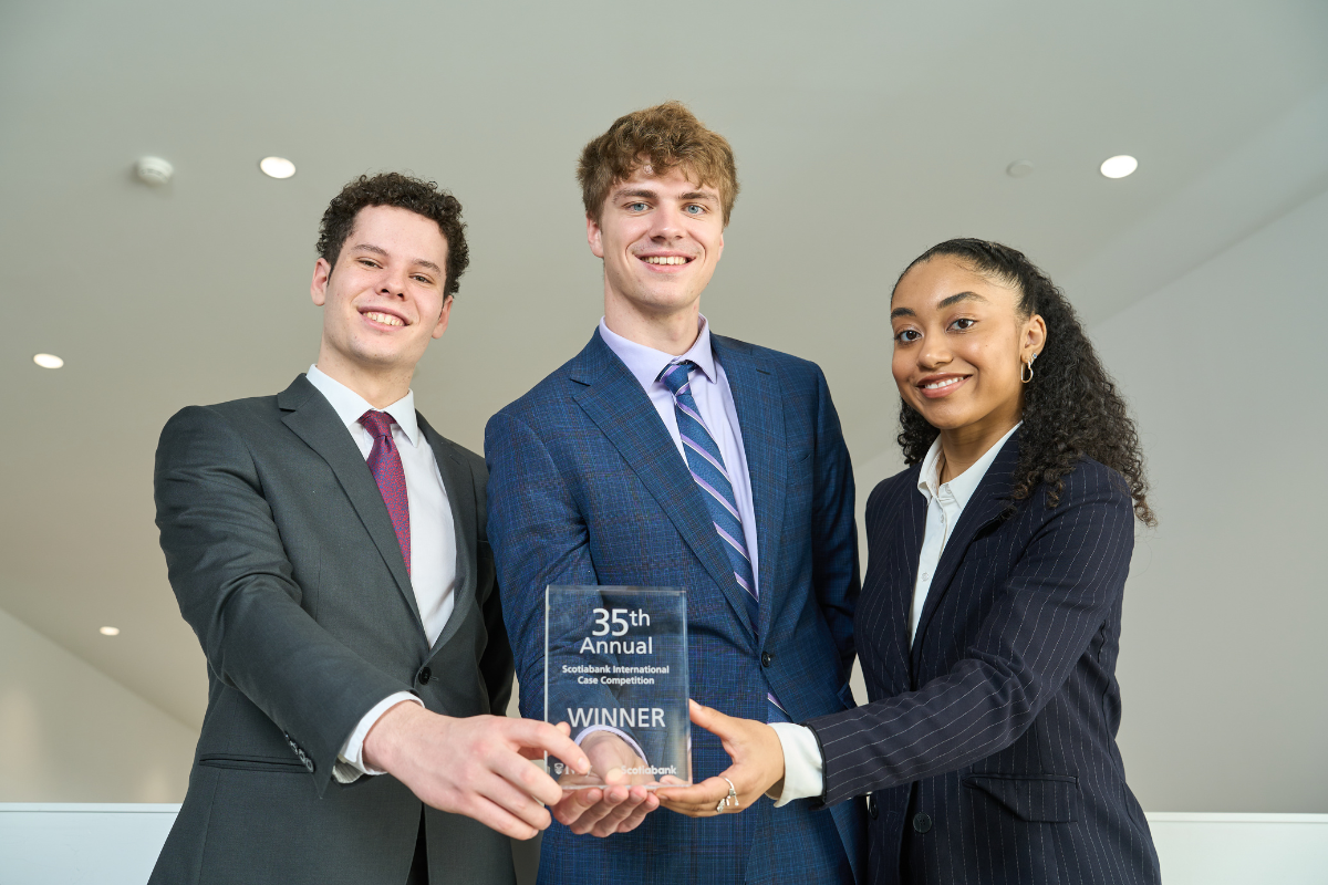 Three students hold up a first-place trophy with pride.