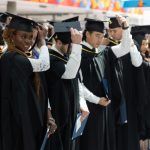 Two rows of dentistry students wear graduation caps and gowns.
