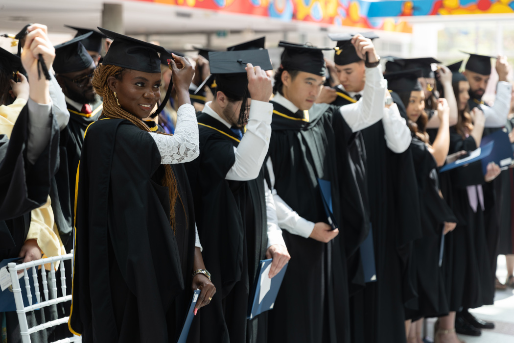 Two rows of dentistry students wear graduation caps and gowns.