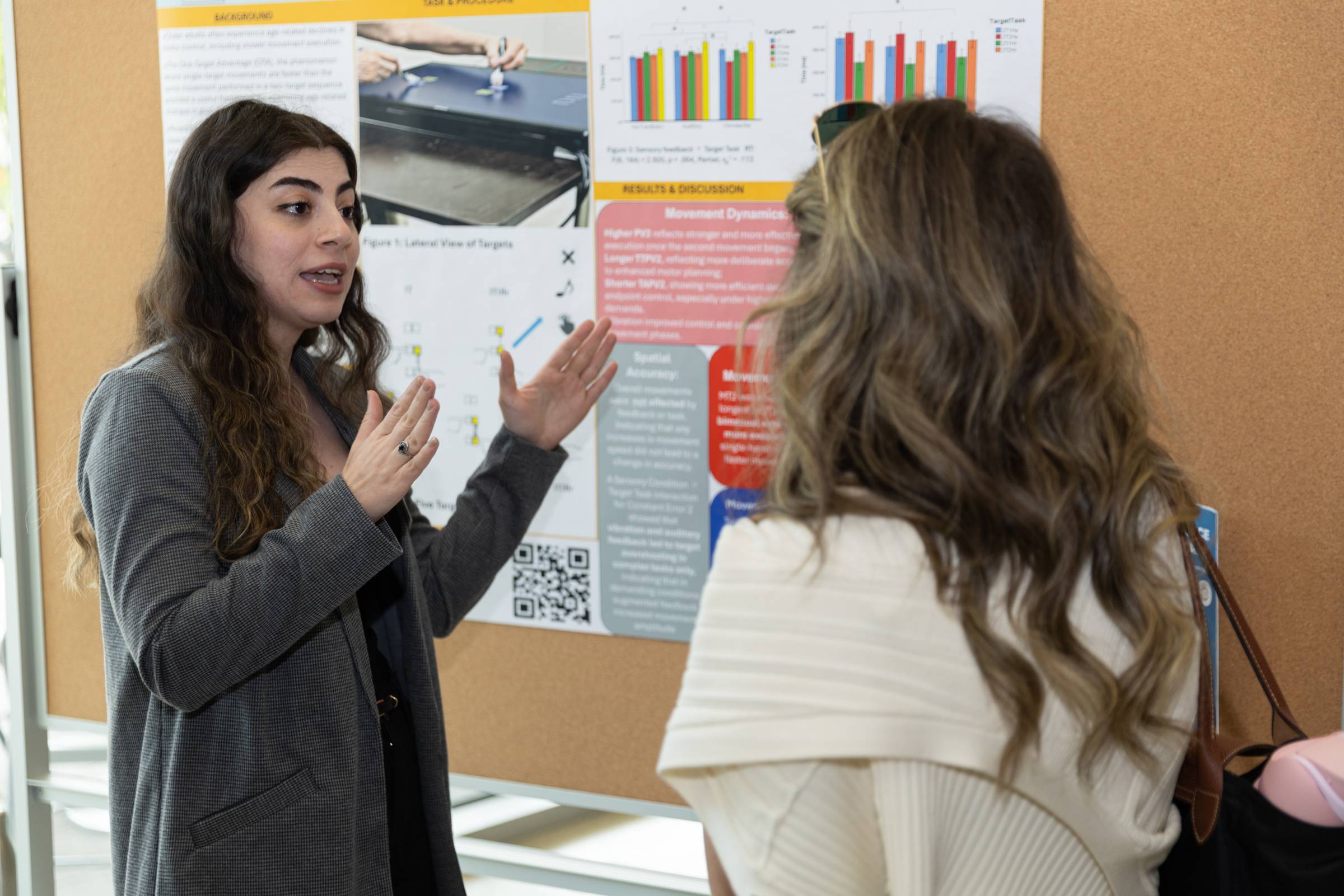 A female student disccues their poster with another student