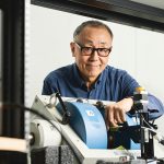 Dr. Can-Ming Hu smiles while adjusting the equipment in his physics lab.