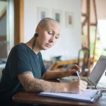 bald head femal professor working at her computer and prepping notes
