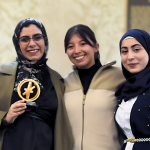 3 individuals standing and posing for a photo with one on the left holding a small trophy.