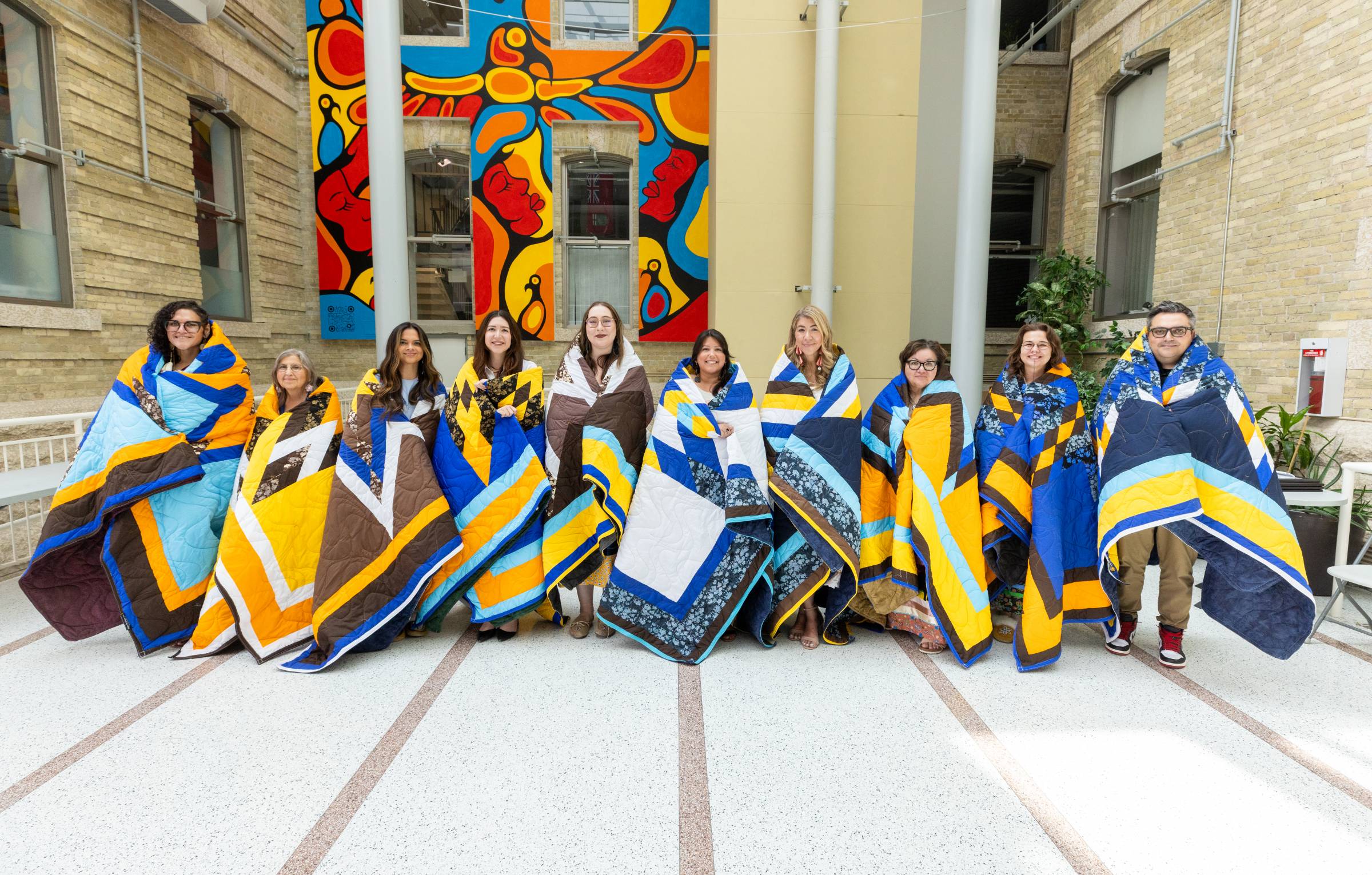 Honourees pose together, each wrapped with their star blanket