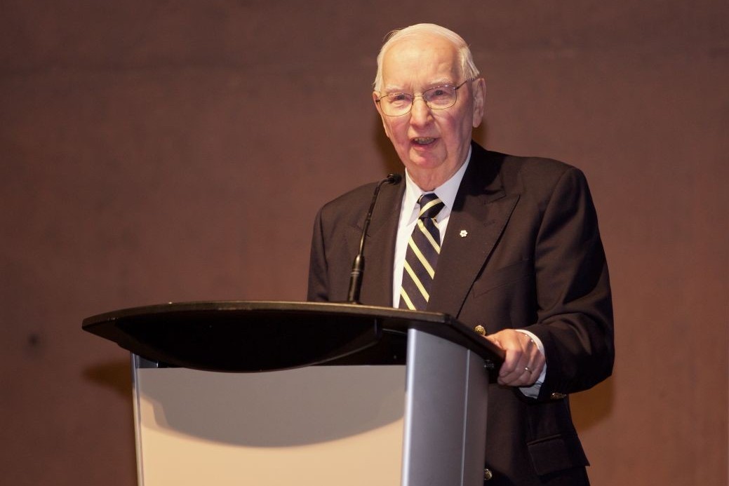 Dr. Henry Friesen speaks at a lectern.