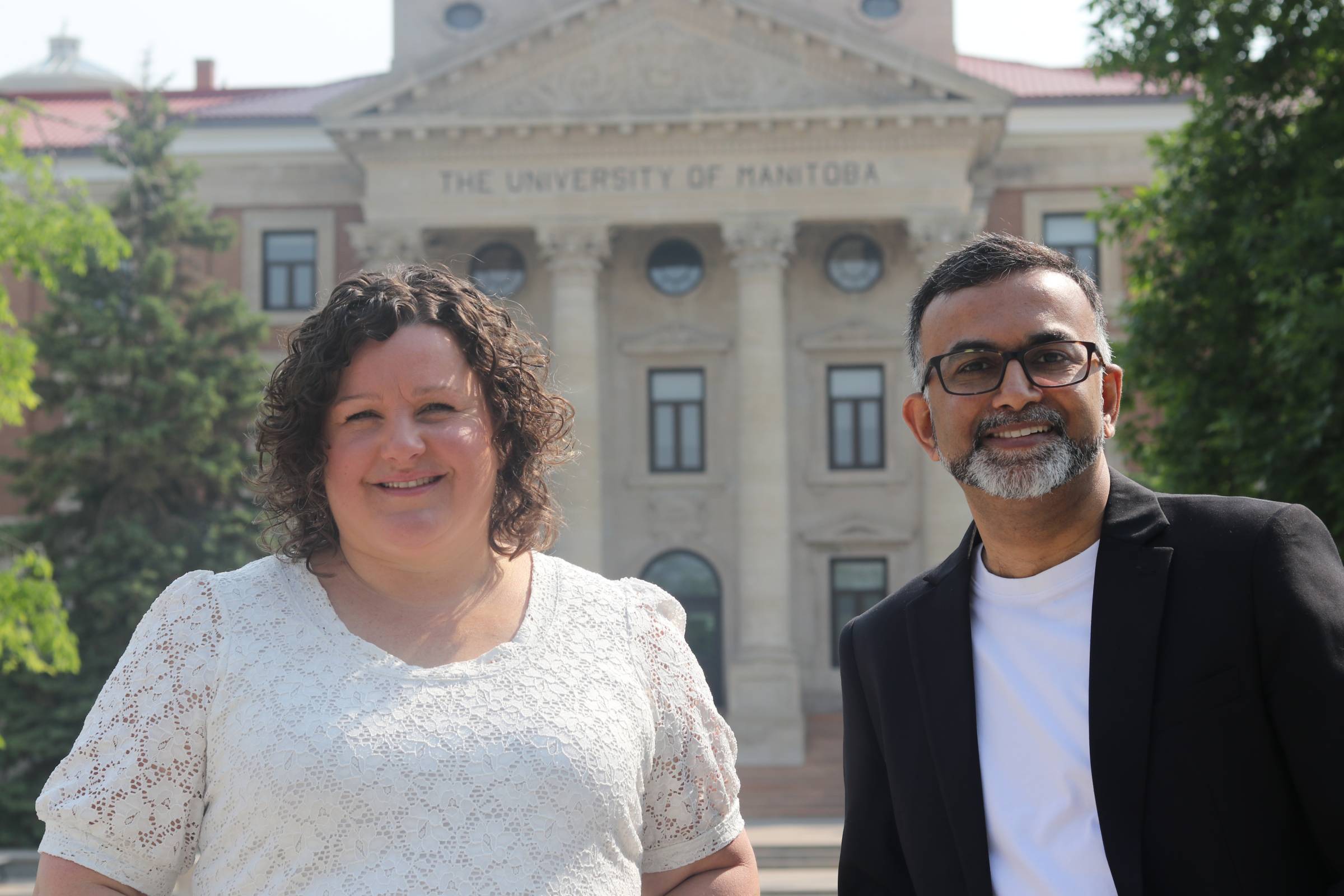 Two people smiling in front of the administration building.