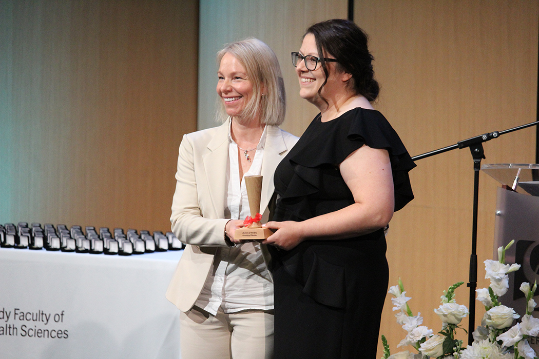 Fleur McEvoy presents a pinard to midwifery graduand Catalina Curé.