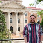 Quinn Neale, a student, standing in front of the Admin Building with trees in the background.