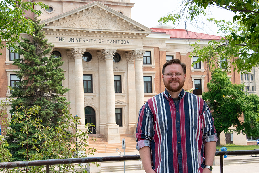 Quinn Neale, a student, standing in front of the Admin Building with trees in the background.