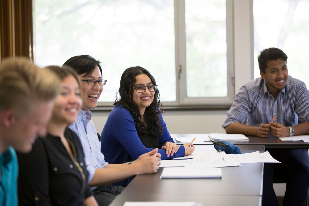 Students smiling at a table, attend an interactive employer information session in Career Services classroom.