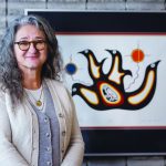 Dr. Moni Fricke with an artwork by Jackson Beardy from Garden Hill First Nation.