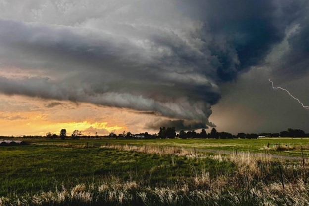 Dark clouds are forming a storm on a grassy field.