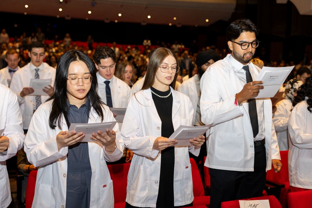Medical students wearing white coats read the Physician's Pledge.