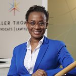 headshot of smiling person in a blue blazer with a sign behind her that says Miller Thomson Avocats Lawyers