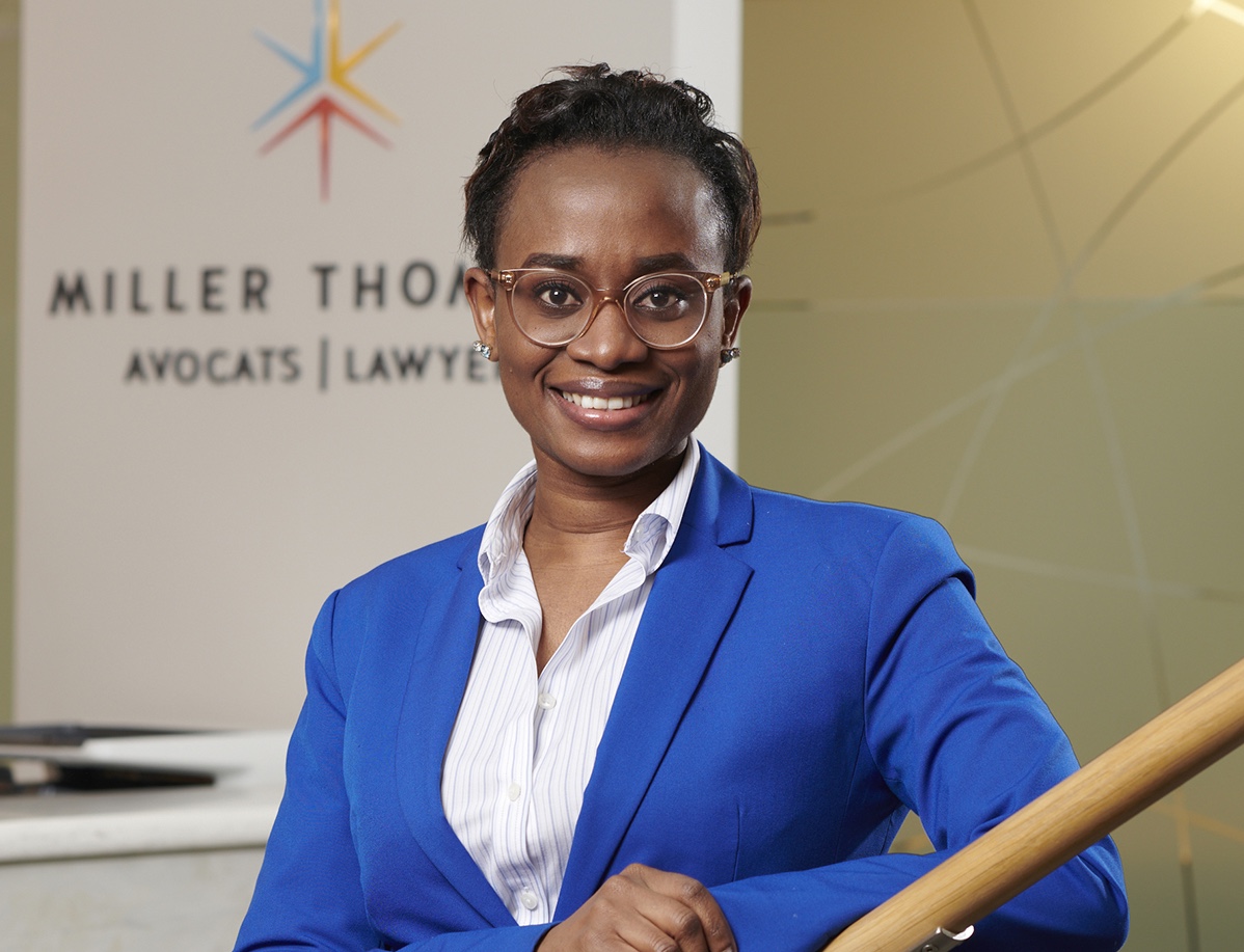 headshot of smiling person in a blue blazer with a sign behind her that says Miller Thomson Avocats Lawyers