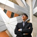 Jae Yun Kim stands in front of architectural supports of a building