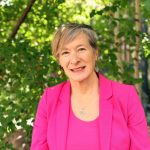Dr. Josée Lavoie smiling while looking at the camera, with small trees in the background.