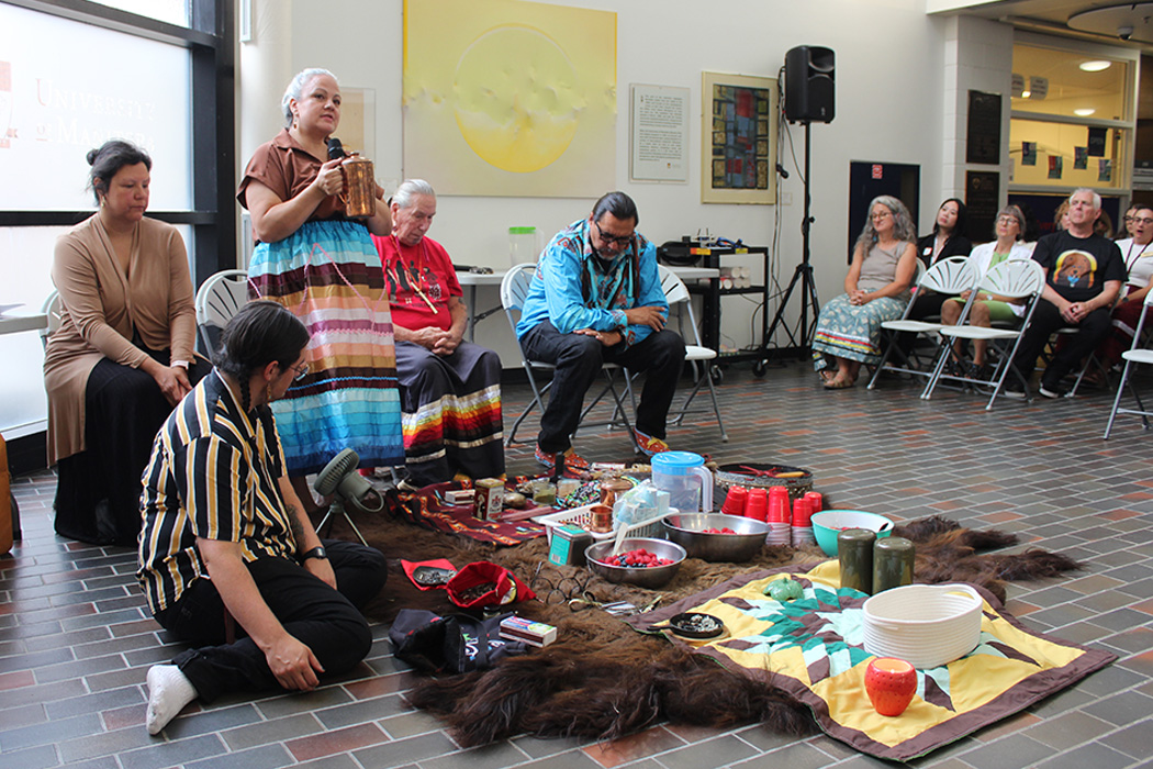 A group of Indigenous leaders around items for a water and pipe ceremony on Bannatyne campus.