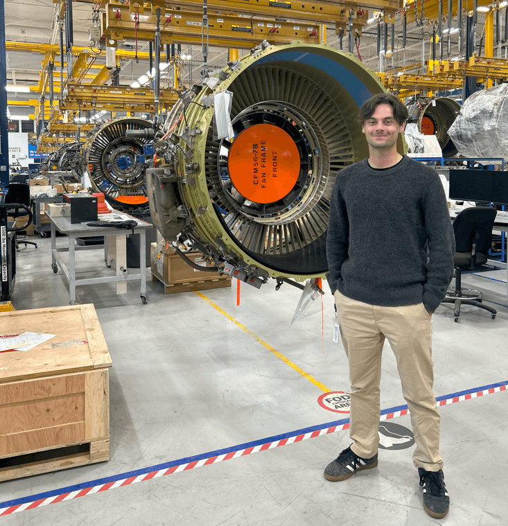 A person standing in a warehouse in front of a large turbine engine