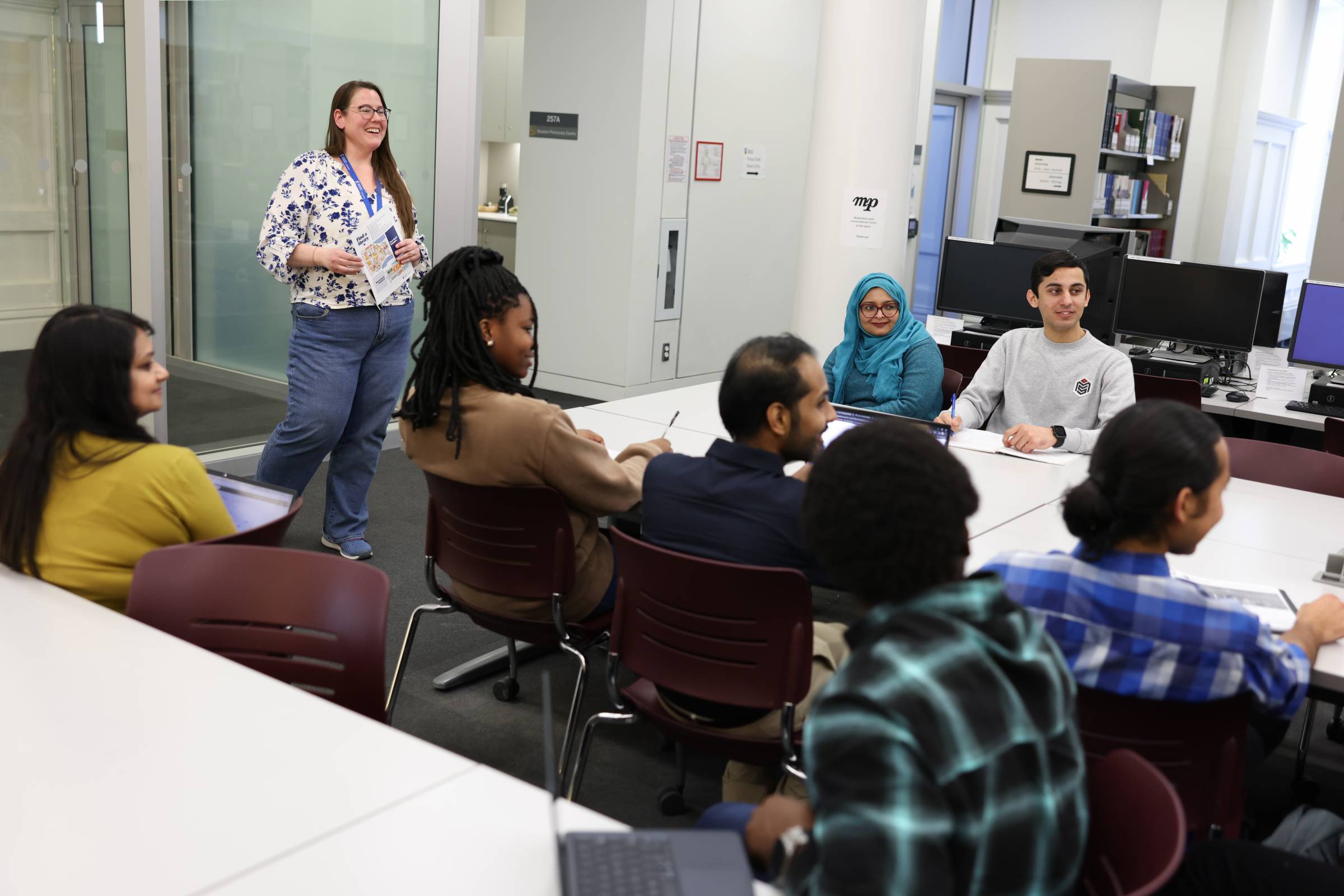Library staff speaking to a group of students in the library