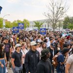 A large group of new UM students gather outside signs stating "We are all Bisons"