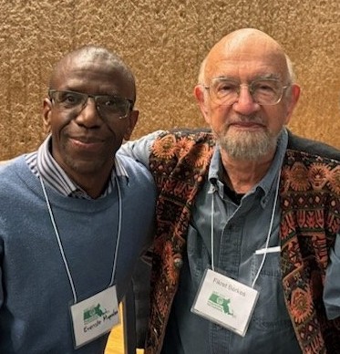 Two people posing for a photo with their arms on each other's back.