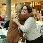 Two alumni embrace at the Dean's Homecoming Breakfast at Bannatyne campus.