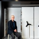 Dr. James Blanchard sitting on a stool in front of rolling filing cabinets