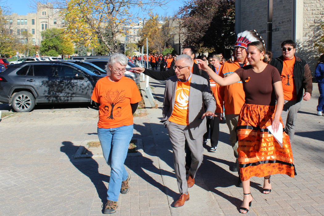 People with orange shirts walk through the University Manitoba Fort Garry campus.