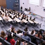 A large class of students at an Indigenous ceremony in a lecture hall.