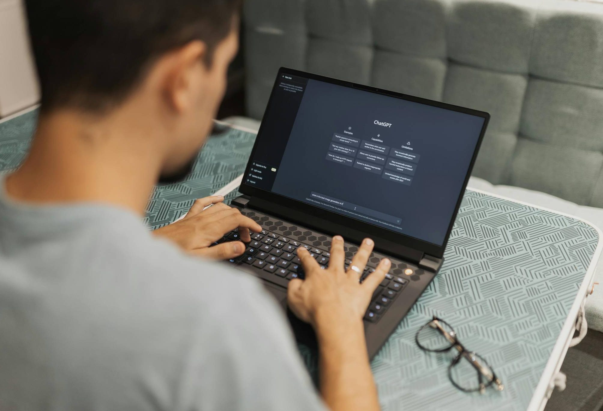 Person sitting at desk with laptop open to ChatGPT homepage.