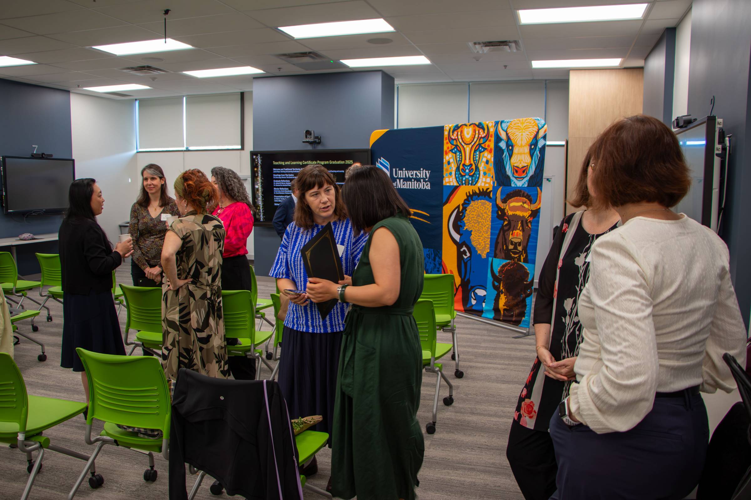 Crowd of people in classroom talking with each other in groups.
