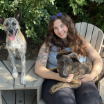 MSW student Emma Cowman, sitting outside with her 2 dogs