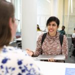 A library staff member helping a student at a service desk