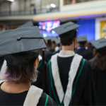 UM students in caps and gowns file into the Convocation space.