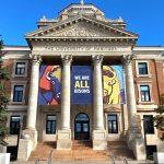 Three banners hang from the Administration Building, two with bison faces and the third with text stating "We are all bisons.: