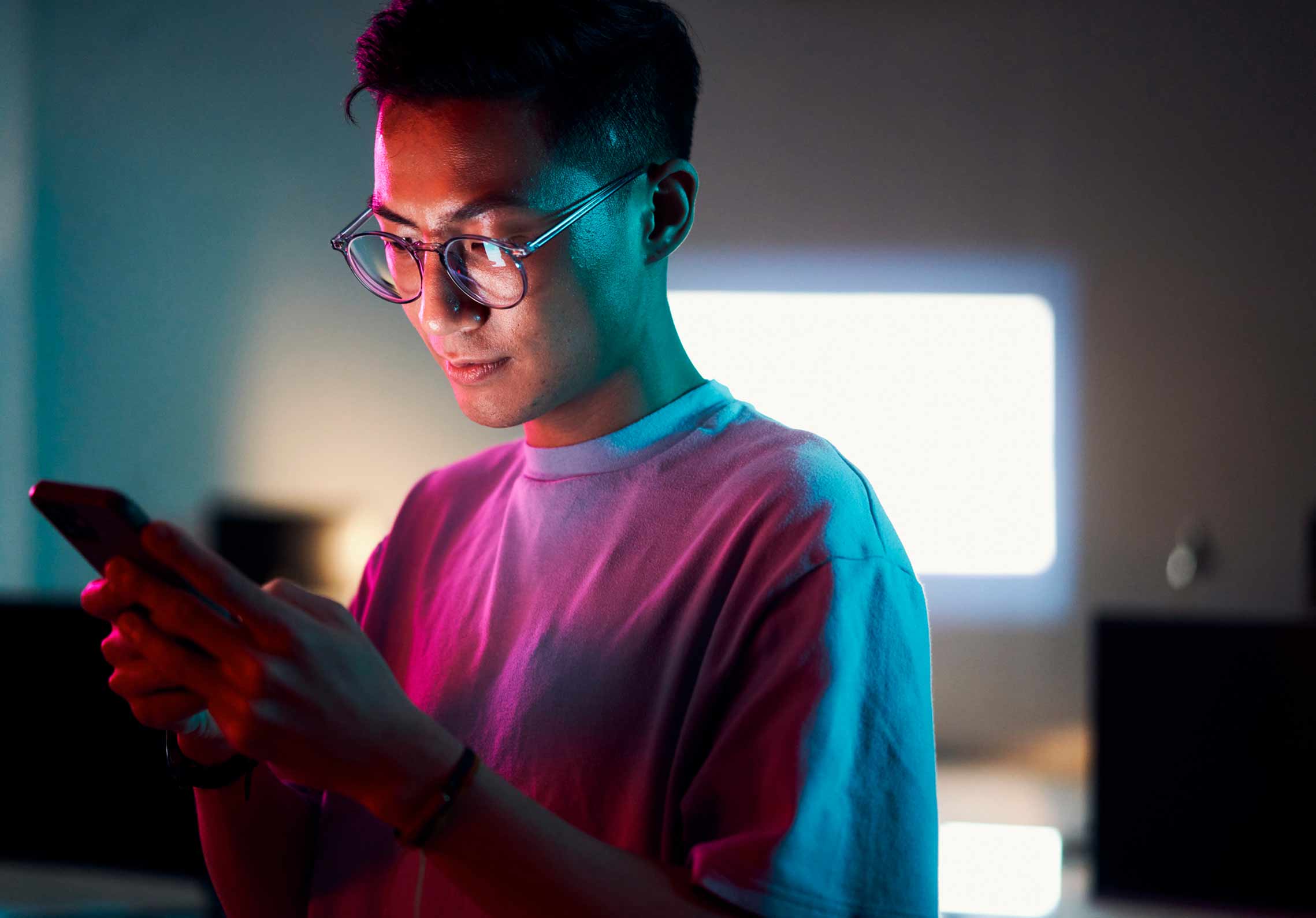 Young man looking at his tablet in a darkly lit room.
