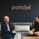 Chancellor Dave Angus sits on a sofa facing entrepreneur and alum Chris Schmidt
