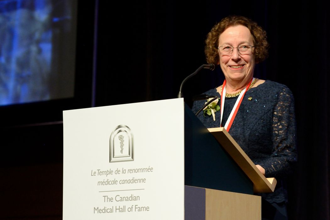 Dr. Estelle Simons stands at a lectern during her induction into the Canadian Medical Hall of Fame.