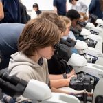 Group of students in a classroom using microscopes.