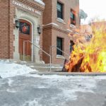 fire burns in fire pit outside of brick building in the winter