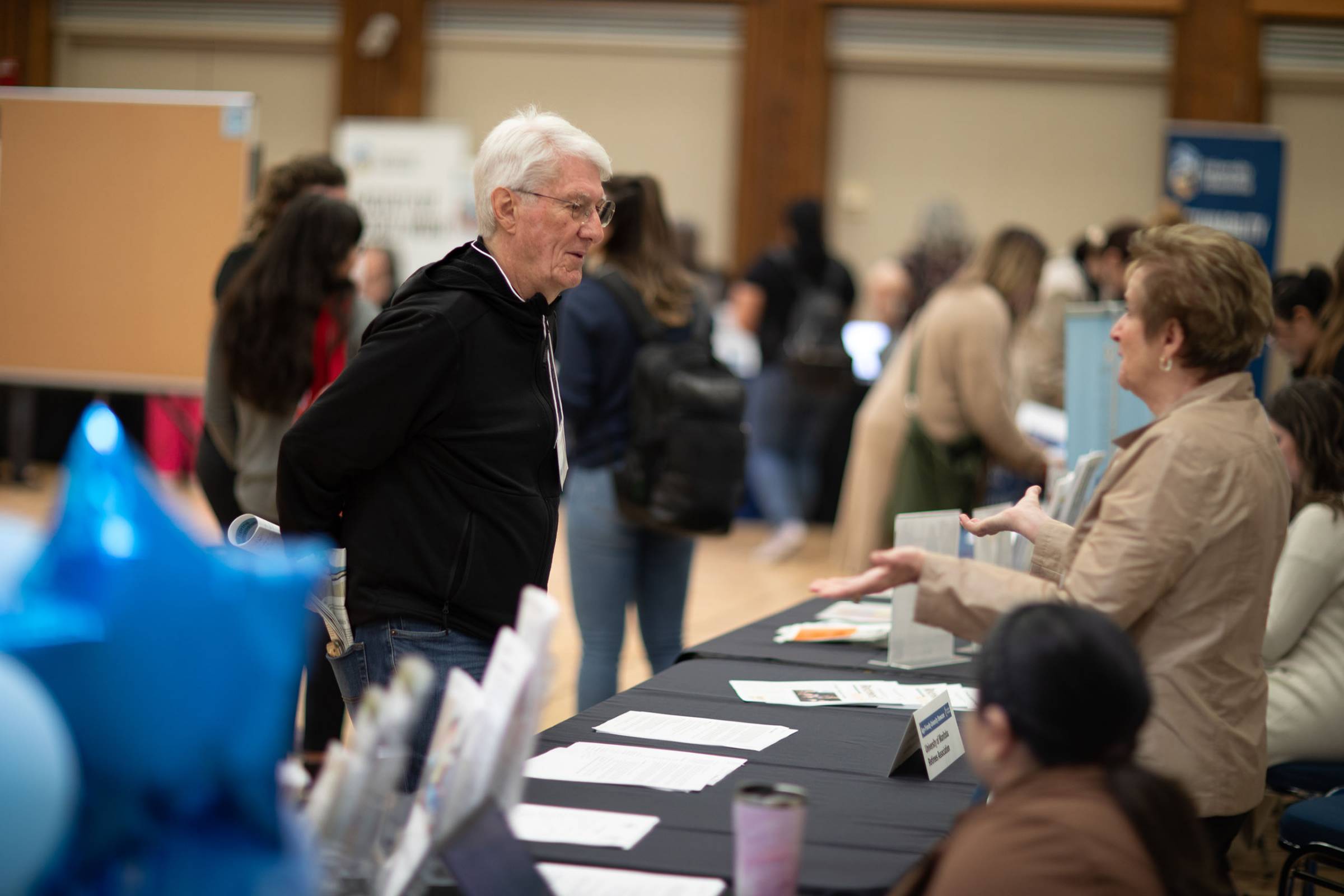 Two people talking by a event booth.