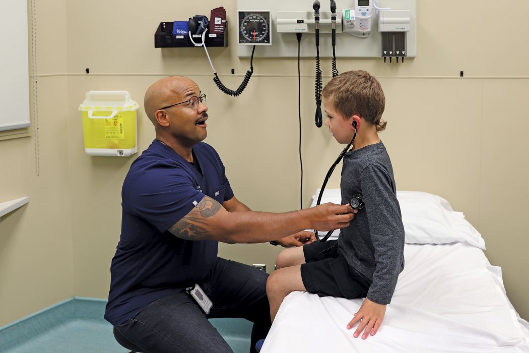 In an examination room, Dr. Jared Bullard lets a child hear his own heartbeat using a stethoscope.